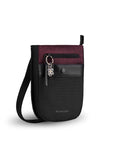 Angled front view of Sherpani’s Anti-Theft bag, the Prima AT in Merlot, with vegan leather accents in black. There is an external pouch on the front of the bag that sits below a locking zipper compartment, which has a ReturnMe tag clipped to it. The bag features an adjustable crossbody strap.