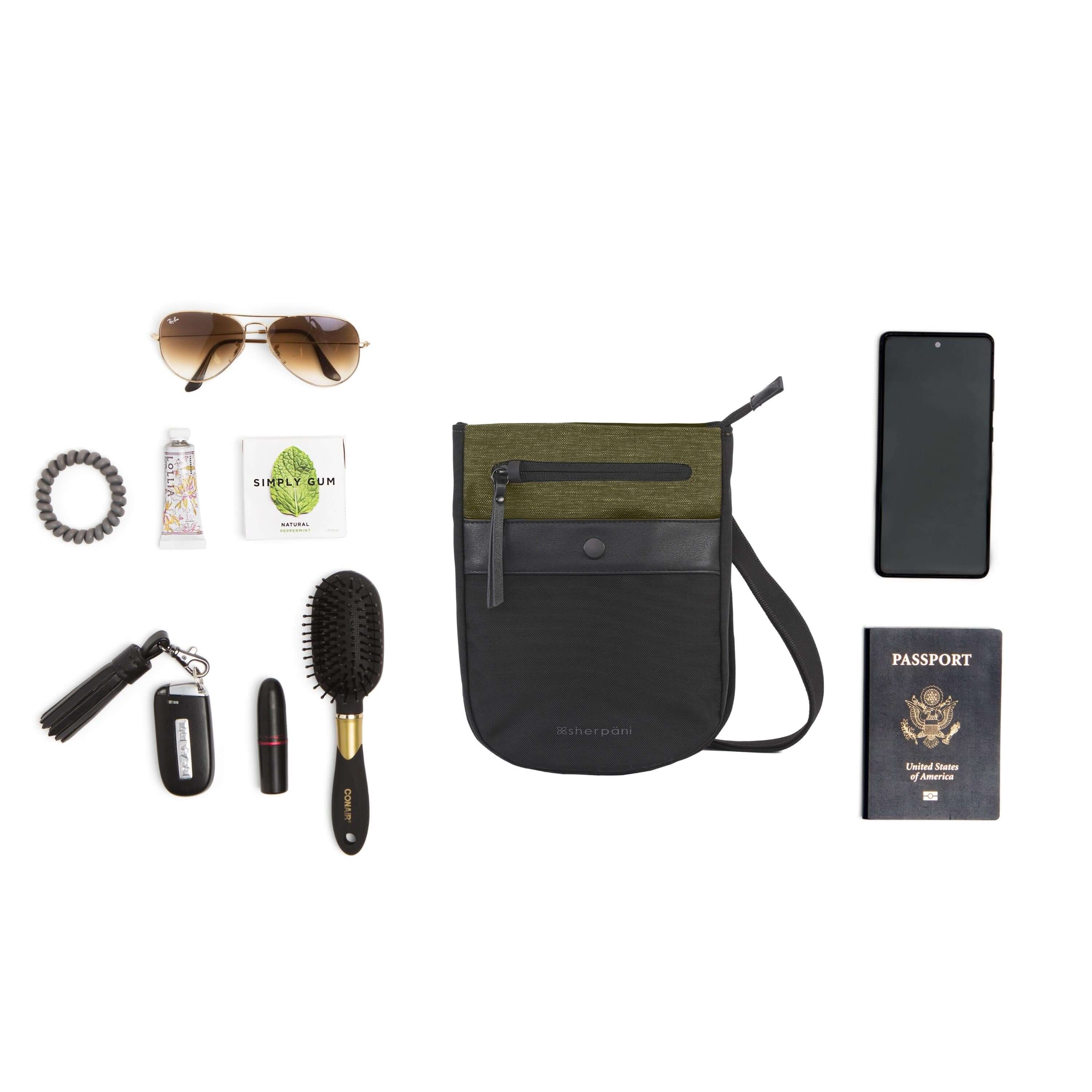 Top view of example items to fill the bag. Sherpani’s Anti-Theft bag, the Prima AT in Loden, lies in the center. It is surrounded by an assortment of items: hairbrush, lipstick, car key, hair tie, lotion, gum, sunglasses, phone and passport. 