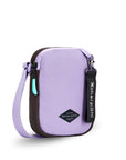Angled front view of Sherpani crossbody, the Rogue in Lavender. The bag is two toned: the front is lavender and the back is brown. The main zipper compartment features an easy-pull zipper accented in aqua. The bag has an adjustable crossbody strap. A branded Sherpani keychain is clipped to a fabric loop on the top right corner.