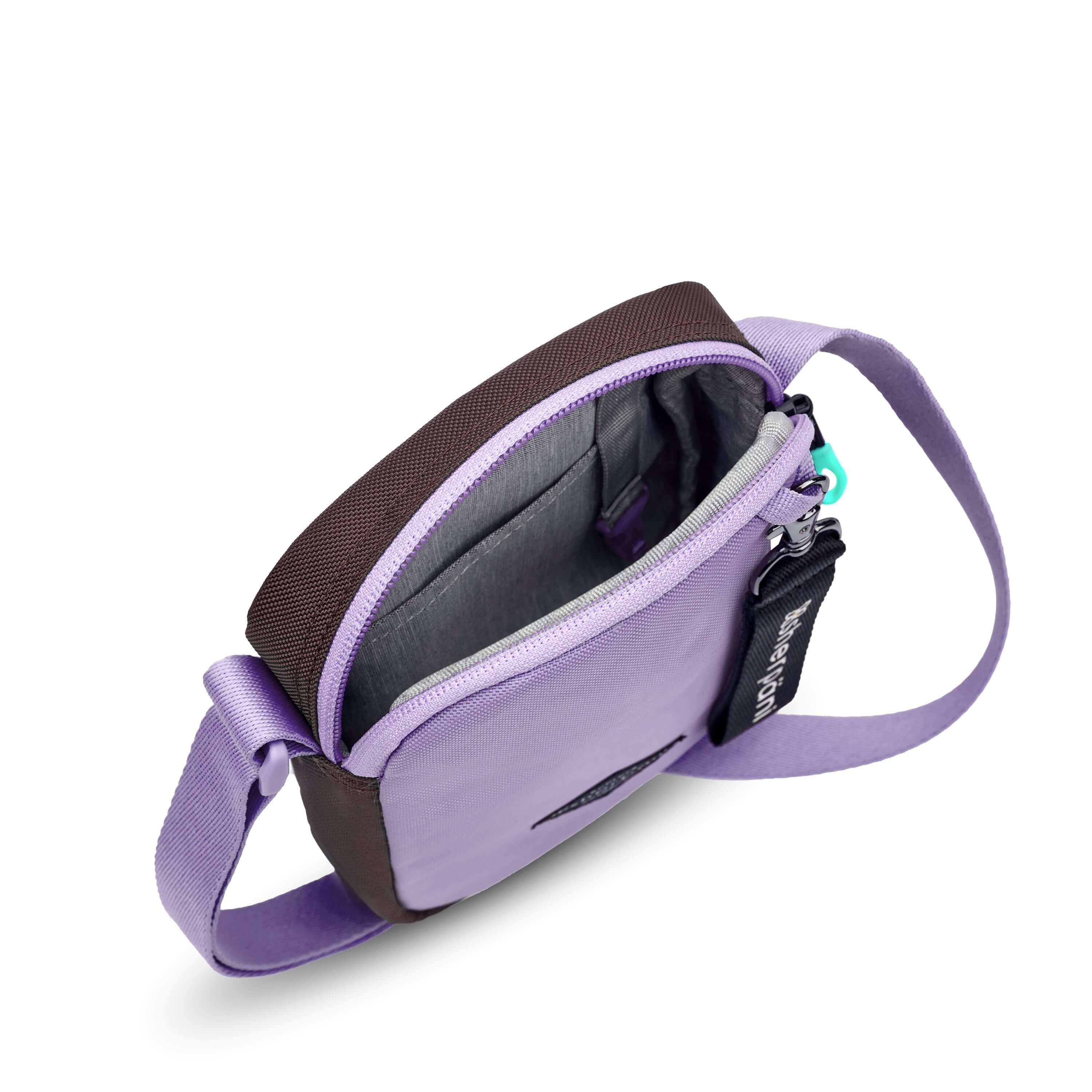 Top view of Sherpani crossbody, the Rogue in Lavender. The main zipper compartment is open to reveal a light gray interior, internal pouch and key fob.