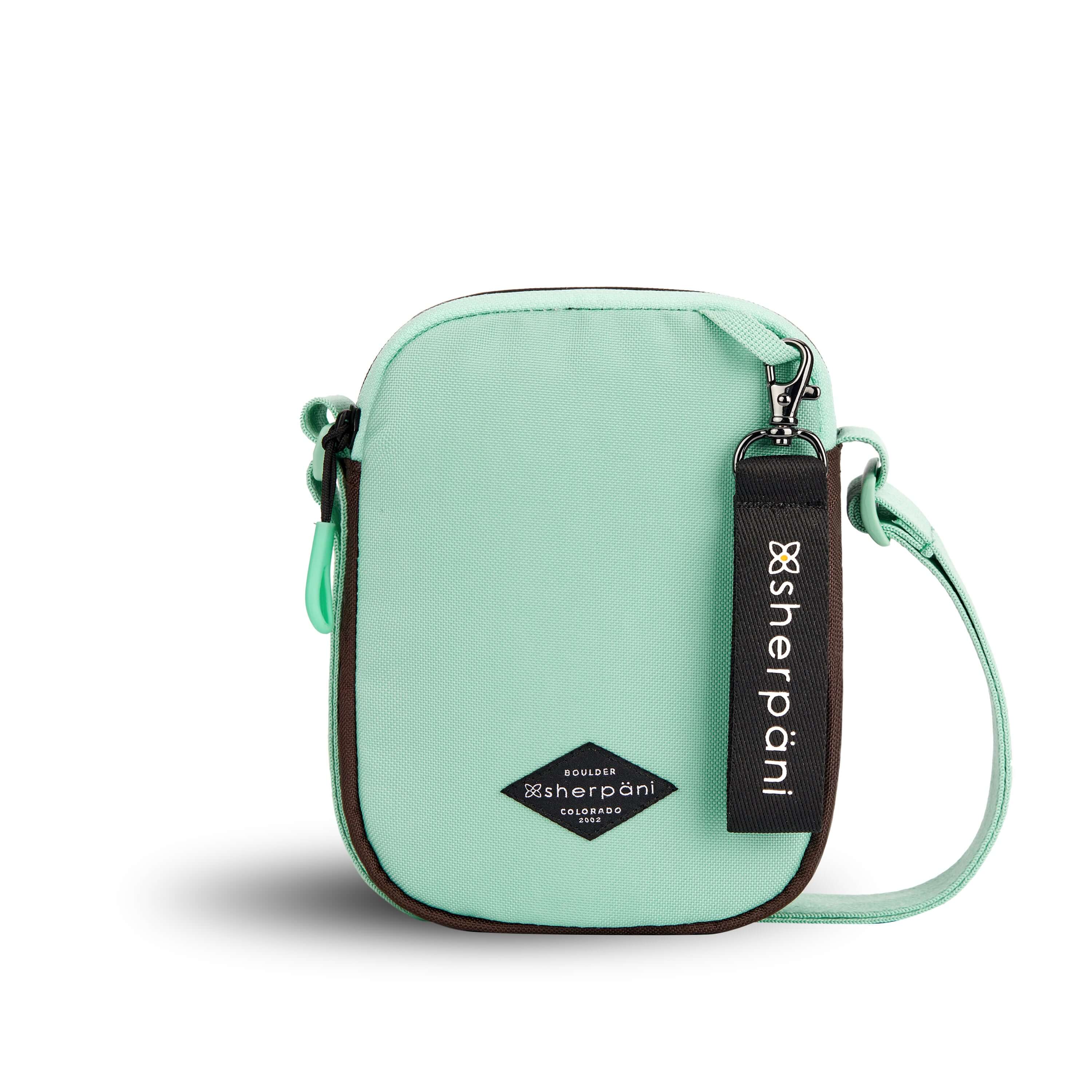 Flat front view of Sherpani crossbody, the Rogue in Seagreen. The bag is two toned: the front is light green and the back is brown. The main zipper compartment features an easy-pull zipper accented in light green. The bag has an adjustable crossbody strap. A branded Sherpani keychain is clipped to a fabric loop on the top right corner.