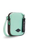 Angled front view of Sherpani crossbody, the Rogue in Seagreen. The bag is two toned: the front is light green and the back is brown. The main zipper compartment features an easy-pull zipper accented in light green. The bag has an adjustable crossbody strap. A branded Sherpani keychain is clipped to a fabric loop on the top right corner.