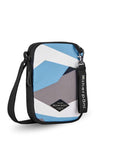 Angled front view of Sherpani crossbody, the Rogue in Summer Camo. The bag is two toned: the front is a camouflage pattern of light blue, gray and white, the back is black. The main zipper compartment features an easy-pull zipper accented in black. The bag has an adjustable crossbody strap. A branded Sherpani keychain is clipped to a fabric loop on the top right corner.
