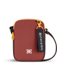 Flat front view of Sherpani mini crossbody purse, the Rogue in Cider. Rogue features include an adjustable crossbody strap, detachable keychain, compact design, minimalist bag and RFID protection. The Cider color is two-toned in burgundy and dark brown with yellow accents.
