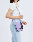 Close up view of a dark haired model facing the side. She is wearing a white tee shirt and jeans. She carries Sherpani crossbody, the Rogue in Lavender, over her shoulder.