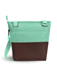 Top view of Sherpani’s crossbody, the Sadie, in Seagreen. The top half of the bag is light green and the bottom half of the bag is brown. There is an external pocket on the back. A zipper pocket sits on one side with an easy-pull zipper that is accented in light green. The bag has an adjustable crossbody strap.