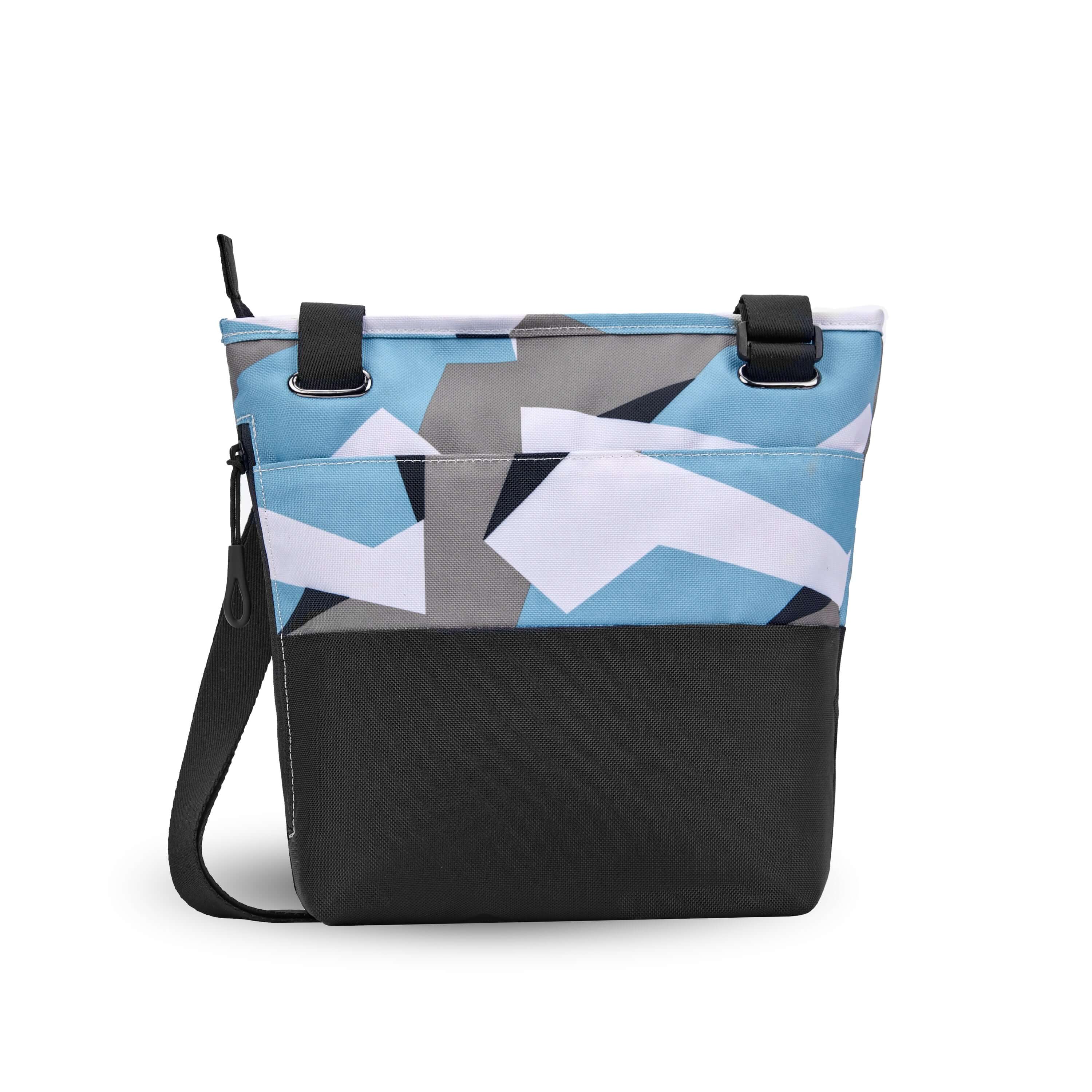 Back view of Sherpani’s crossbody, the Sadie, in Summer Camo. The top half of the bag is a camouflage pattern of white, gray and light blue, the bottom half of the bag is black. There is an external pocket on the back. A zipper pocket sits on one side with an easy pull zipper that is accented in black. The bag has an adjustable crossbody strap. 