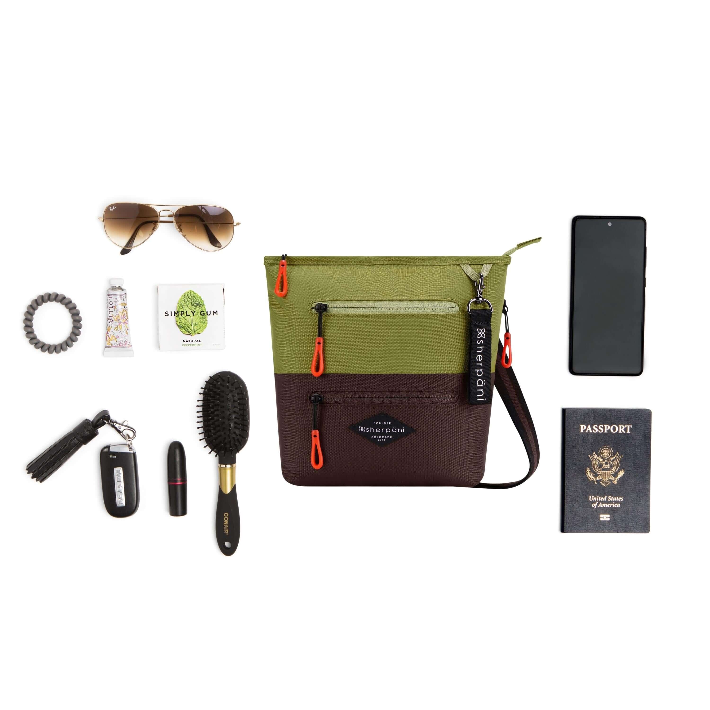 Top view of example items to fill the bag. Sherpani crossbody, the Sadie in Cactus, lies in the center. It is surrounded by an assortment of items: sunglasses, hair tie, hand lotion, gum, car key, lipstick, hair brush, phone and passport. 