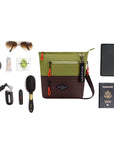 Top view of example items to fill the bag. Sherpani crossbody, the Sadie in Cactus, lies in the center. It is surrounded by an assortment of items: sunglasses, hair tie, hand lotion, gum, car key, lipstick, hair brush, phone and passport.