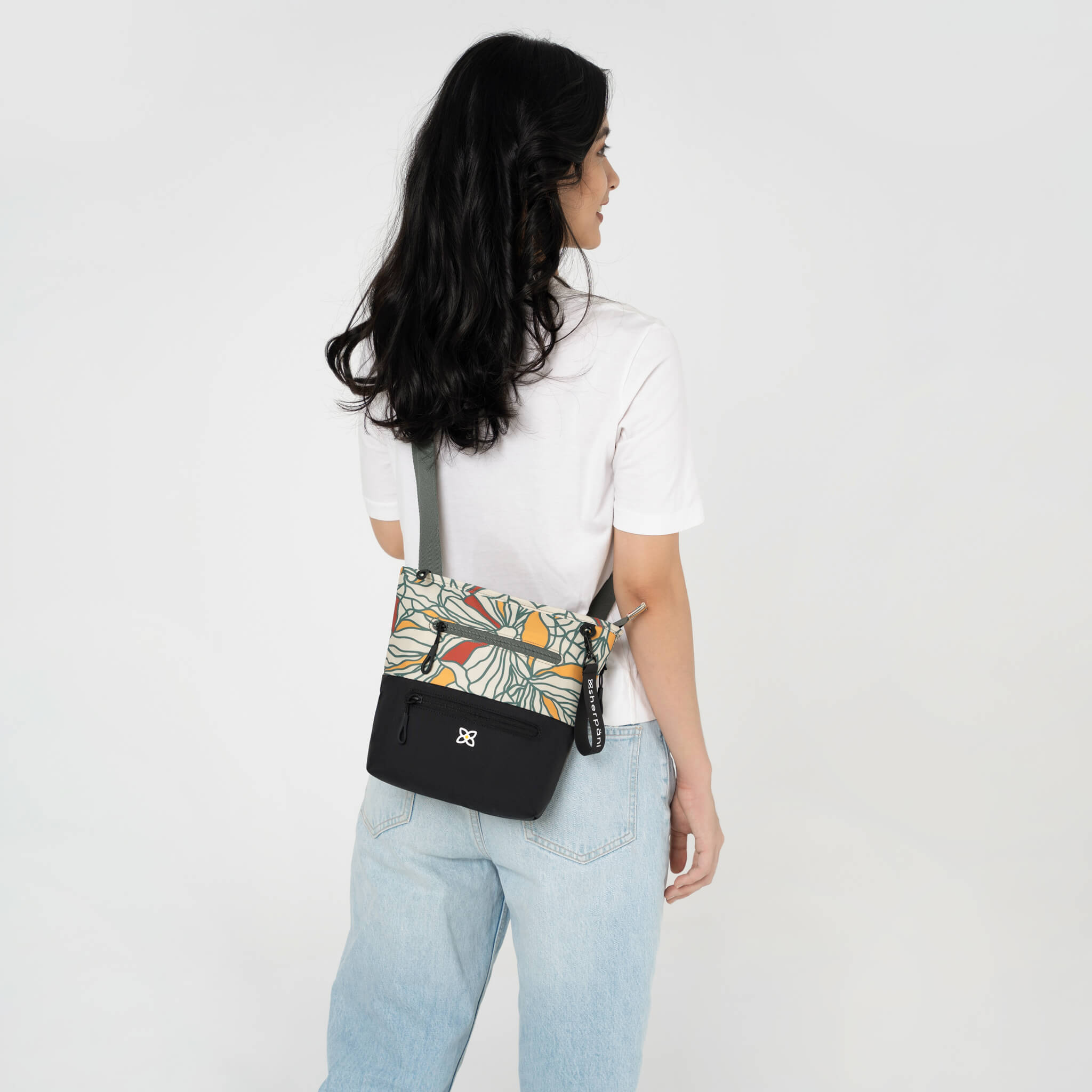 A model wearing Sherpani crossbody with RFID protection, the Sadie in Fiori. 