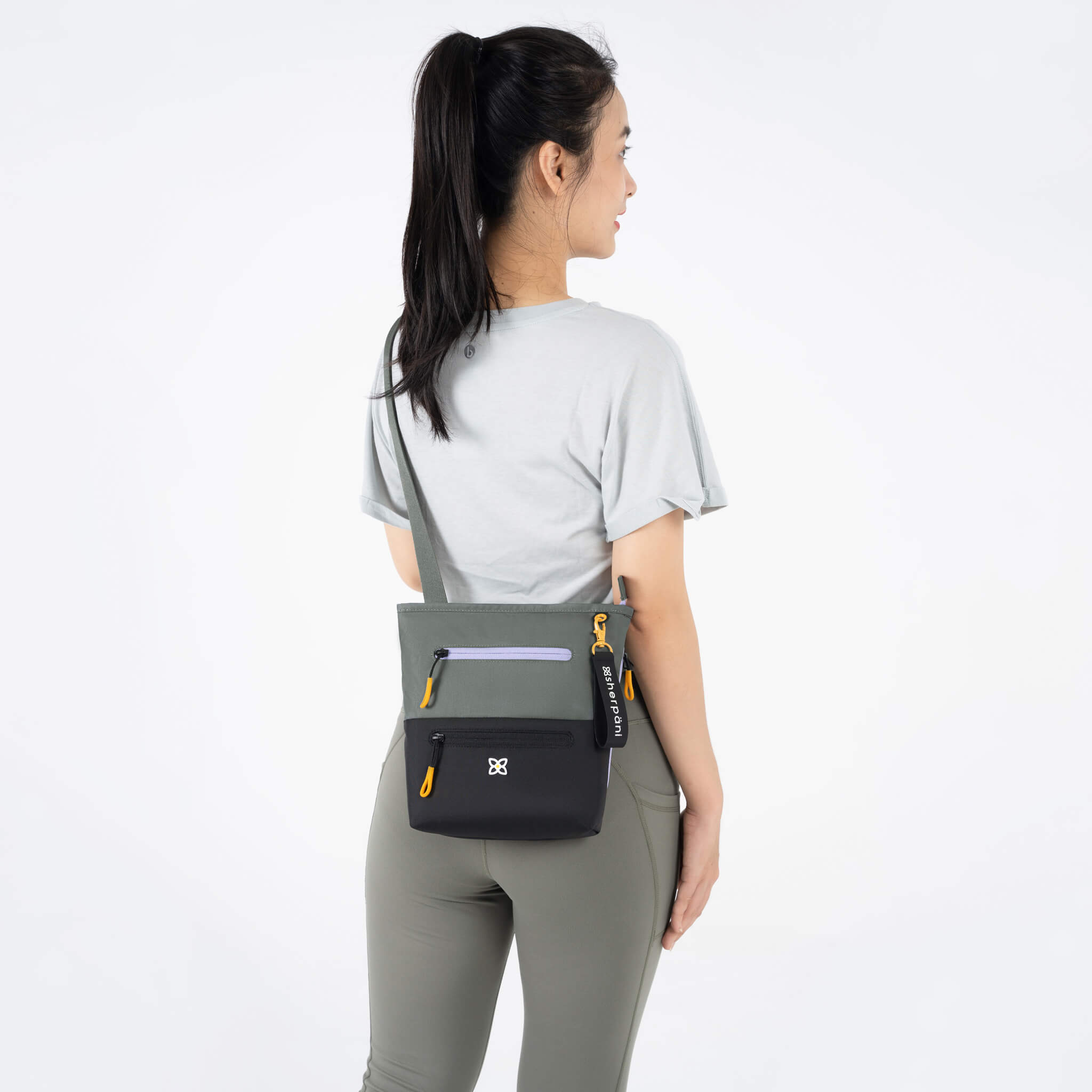 A model showing Sherpani RFID crossbody purse, the Sadie in Juniper. 