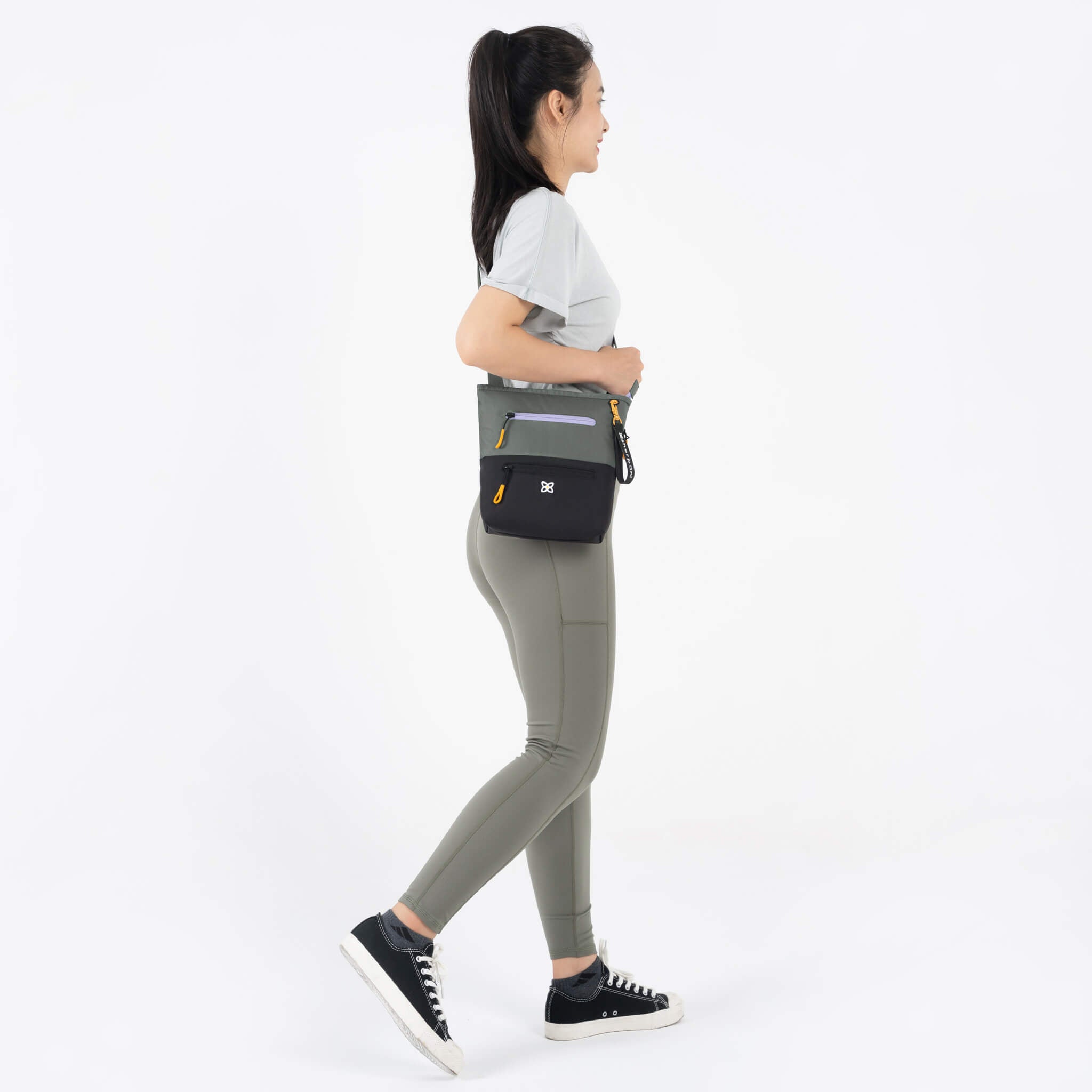 A model wearing Sherpani RFID crossbody bag, the Sadie in Juniper. 