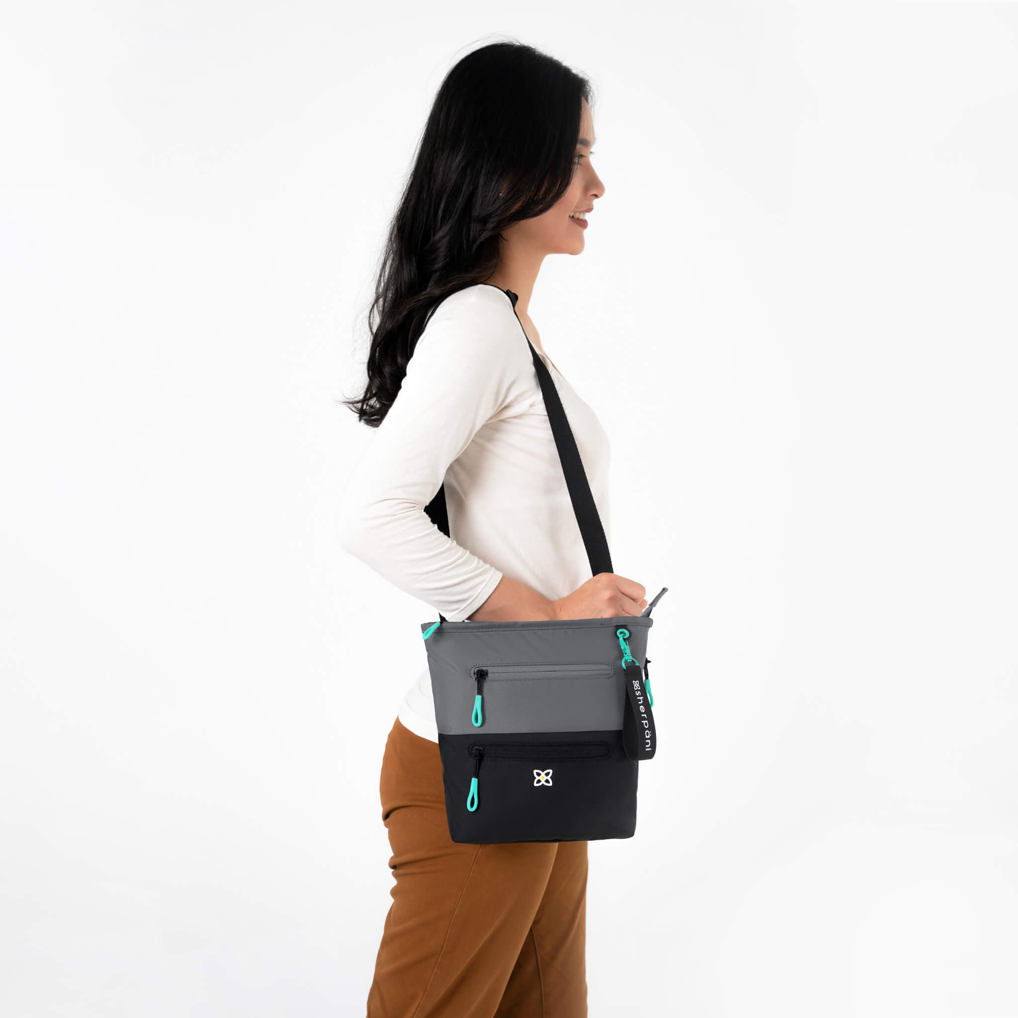 A model showing Sherpani travel bag made from recycled materials, the Sadie in Moonstone. 