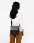 A model wearing Sherpani sustainable travel bag, the Sadie in Moonstone.