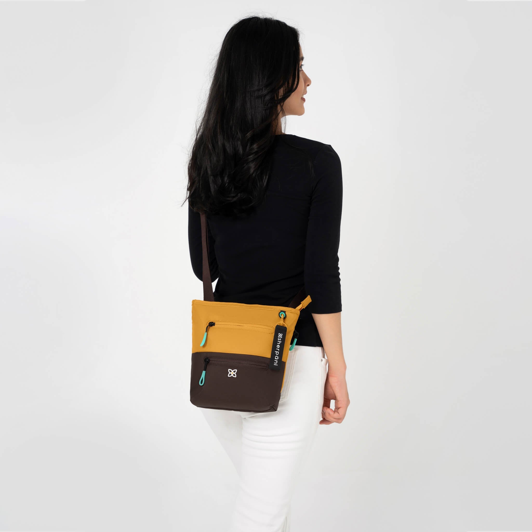 A model wearing Sherpani RFID travel purse, the Sadie in Sundial. 