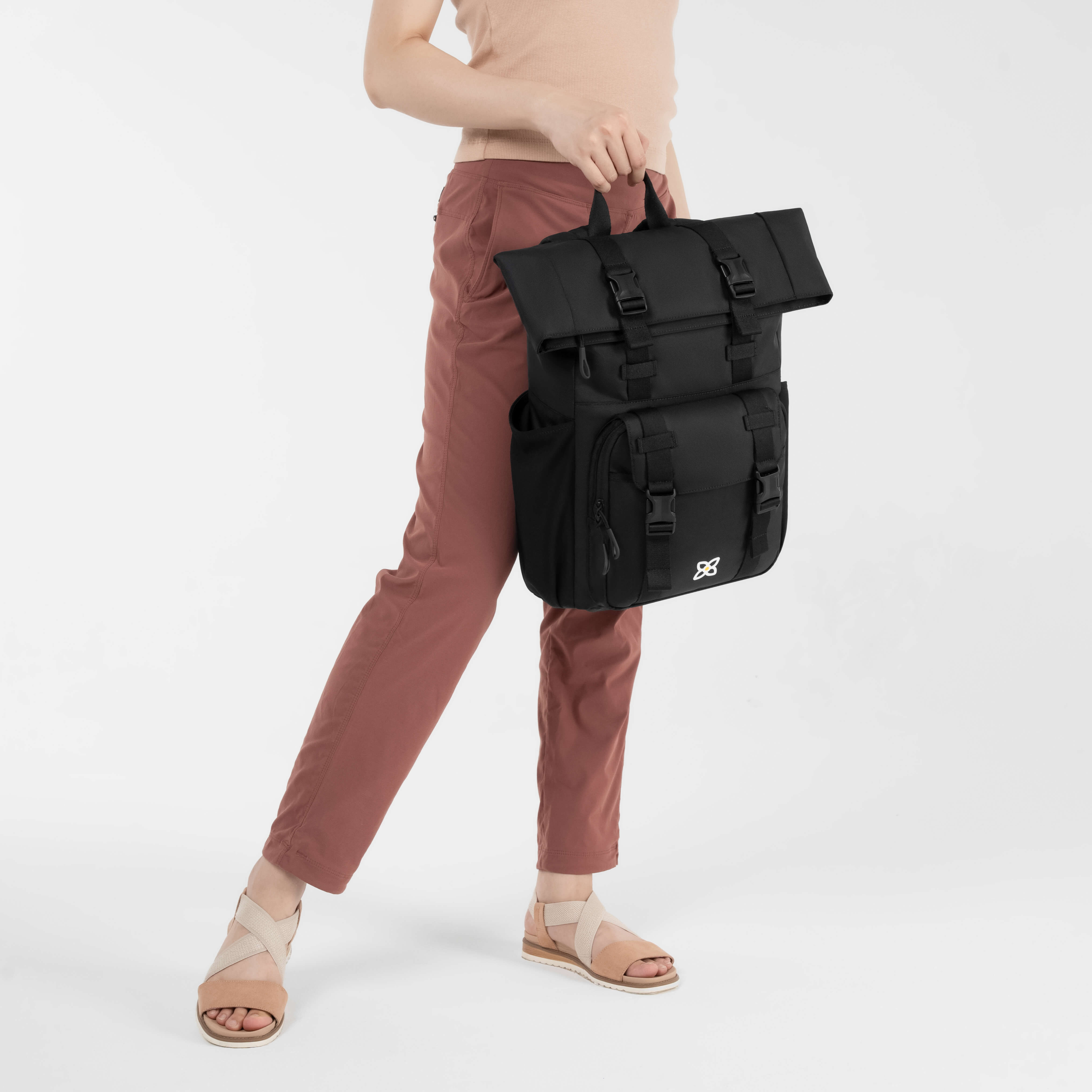 A model holding the carrying handle of the women's travel backpack, the Sedona in Raven. 