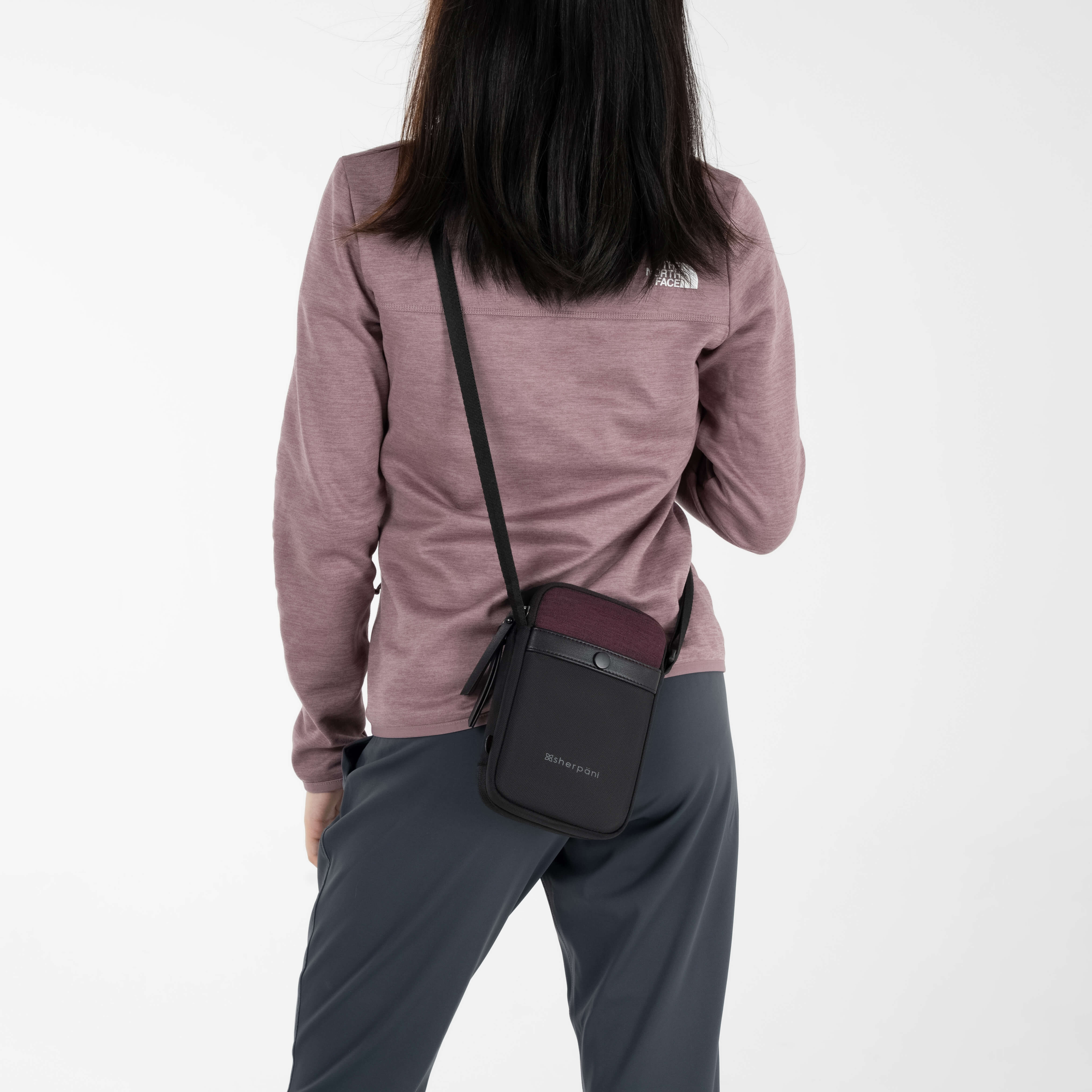 A model wearing Sherpani anti-theft crossbody purse wallet, the Simplicity in Merlot. 