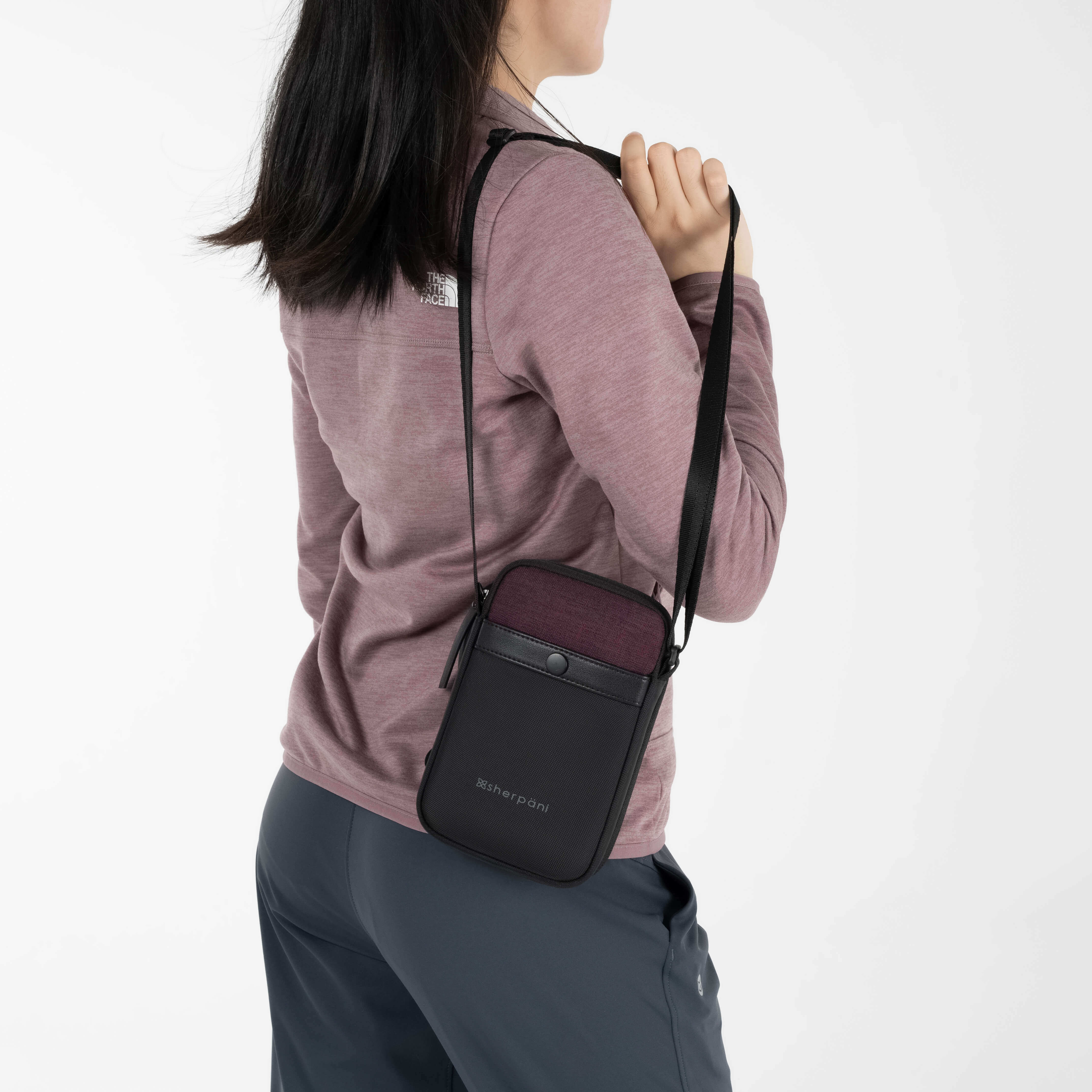 A woman wearing the Simplicity in Merlot as a small shoulder bag for travel. 