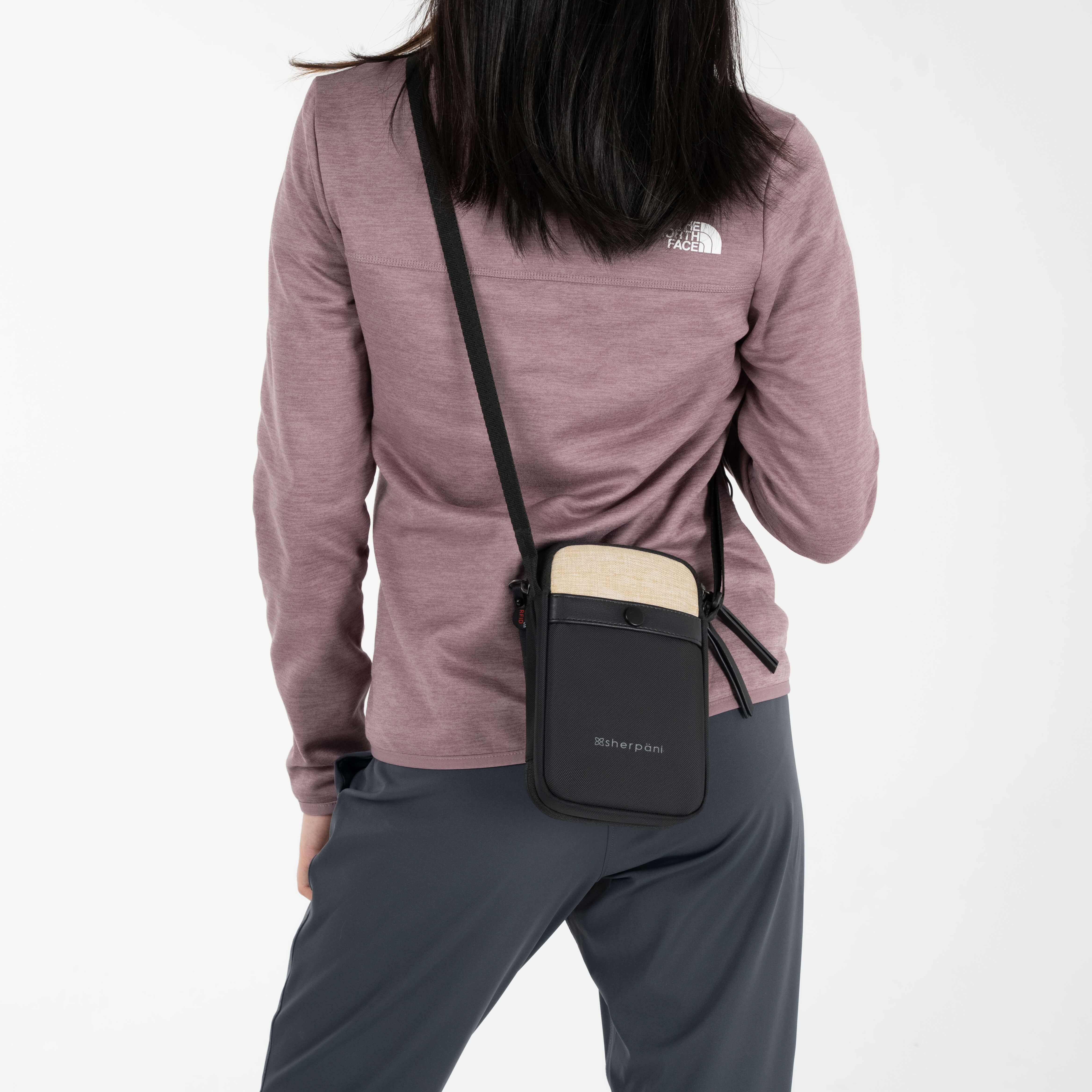 Woman wearing Sherpani crossbody wallet design, the Simplicity in Straw. 