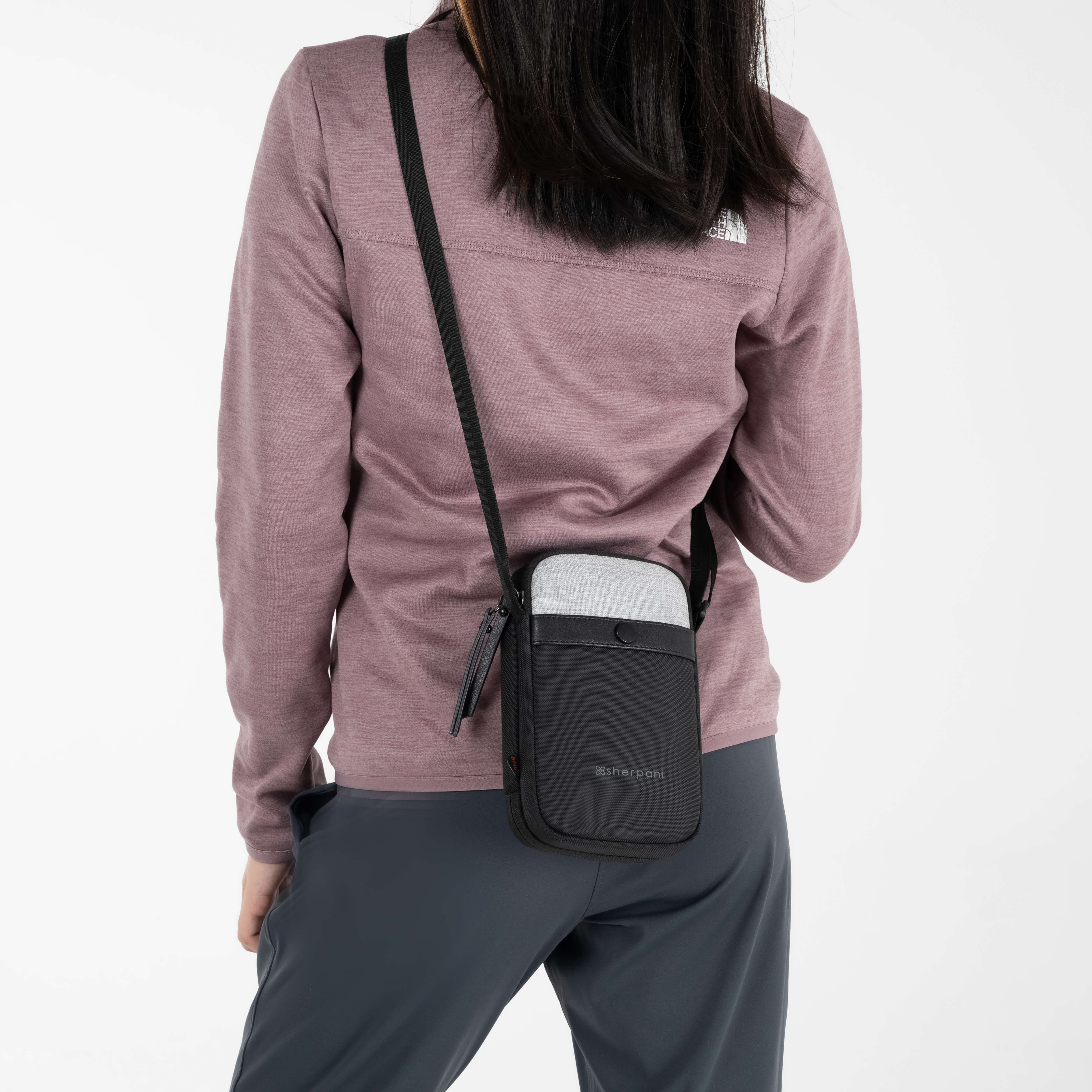 A woman wearing Sherpani anti-theft crossbody wallet, the Simplicity in Sterling. 