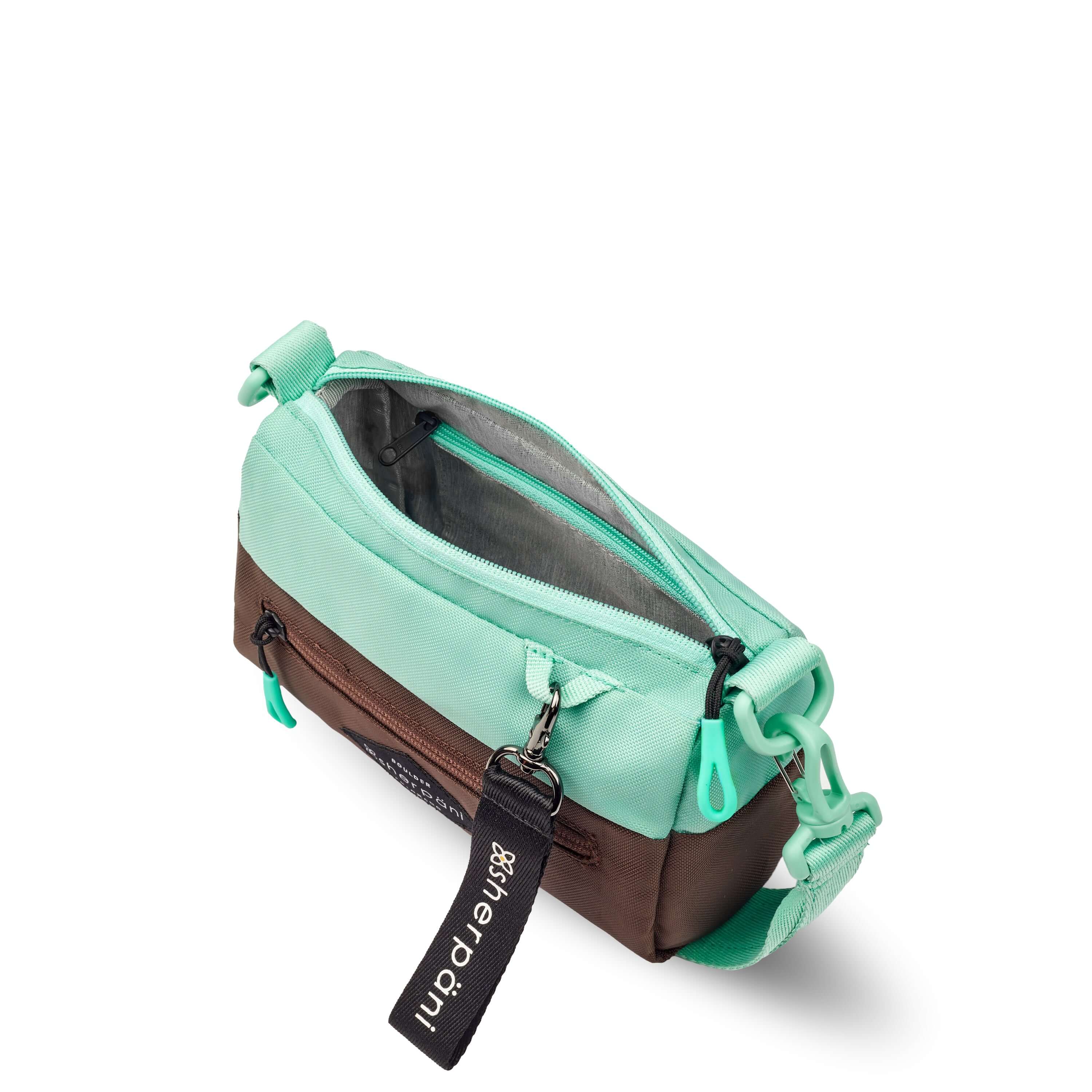 Top view of Sherpani's purse, the Skye in Seagreen. The main zipper compartment is open to reveal a light gray interior and an internal zipper pocket. 