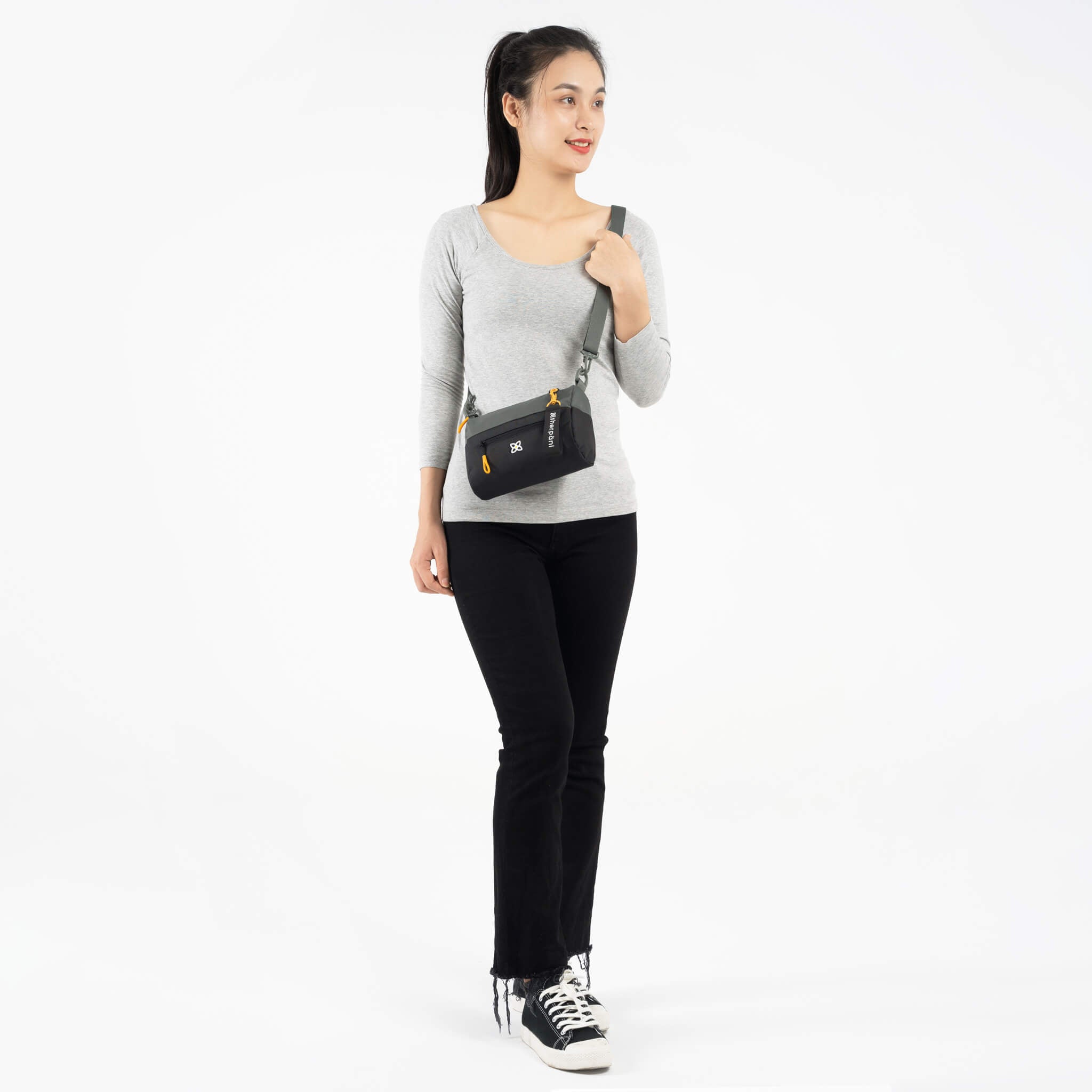 A model wearing Sherpani RFID blocking purse, the Skye in Juniper, as a crossbody bag.