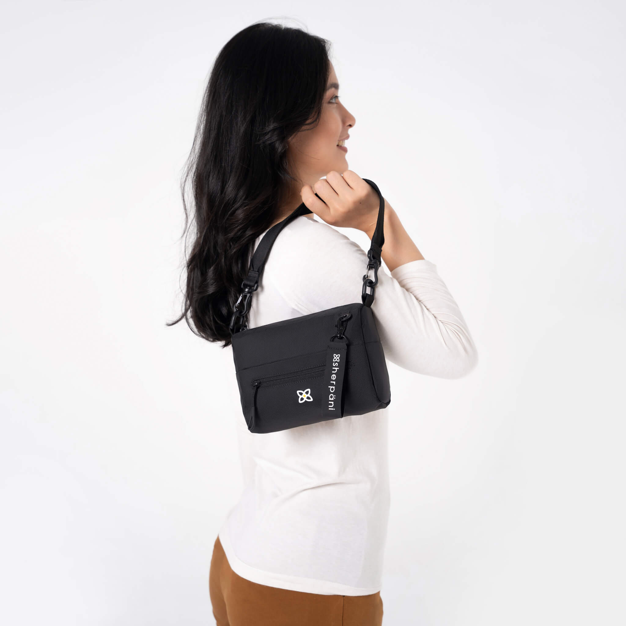 A model showing Sherpani RFID bag, the Skye in Raven, a purse made from recycled plastic bottles. 