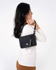 A model showing Sherpani RFID bag, the Skye in Raven, a purse made from recycled plastic bottles.