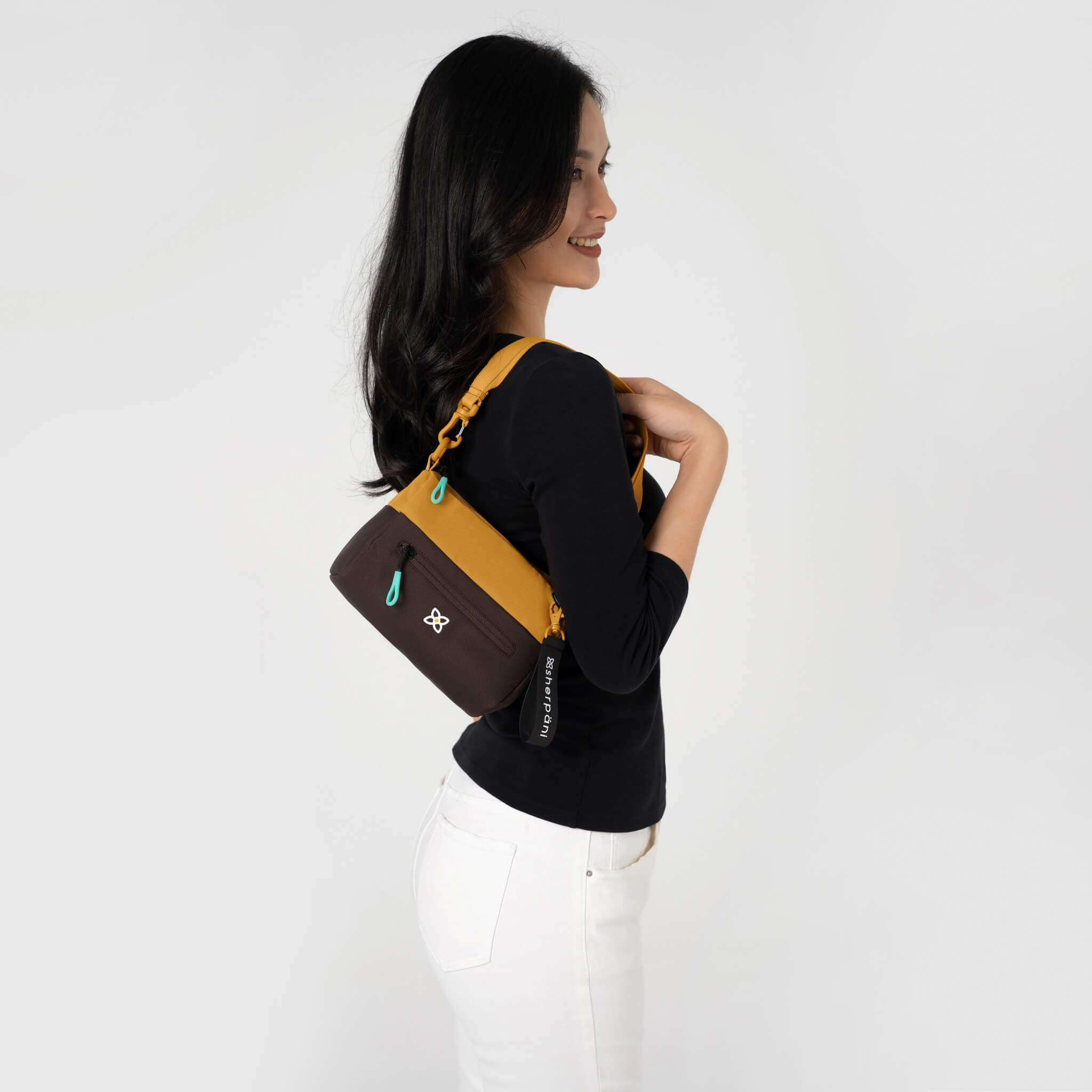 A model showing the small shoulder bag style of Sherpani handbag, the Skye in Sundial. 