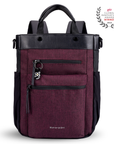 Flat front view of Sherpani's Anti-Theft bag, the Soleil AT in Merlot, with vegan leather accents in black. On the front are two locking zipper compartments, a ReturnMe tag is clipped to the upper one. Two elastic water bottle holders sit on either side of the bag. It has padded backpack straps, short tote handles, and a place to attach a crossbody strap.