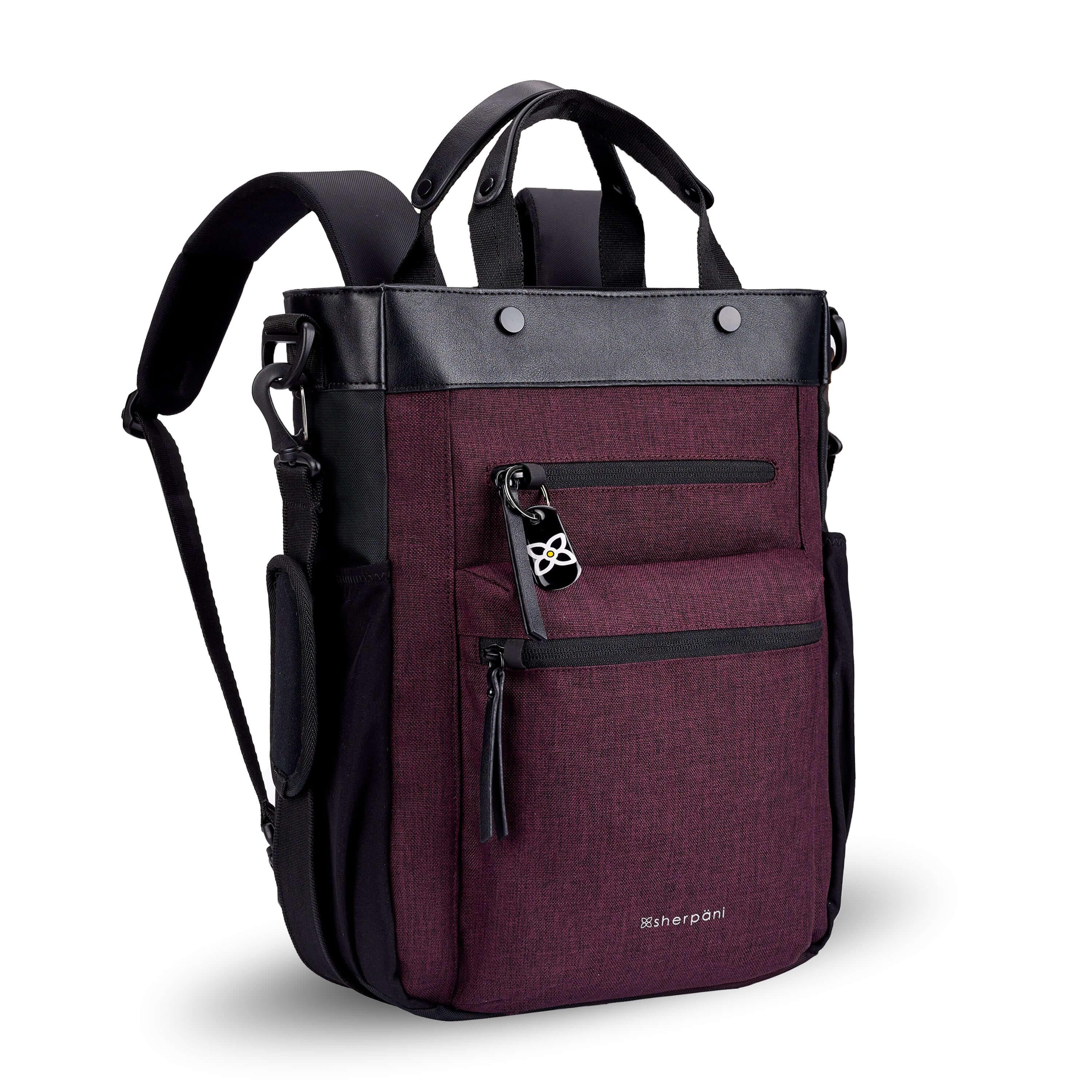 Angled front view of Sherpani&#39;s Anti-Theft bag, the Soleil AT in Merlot, with vegan leather accents in black. On the front are two locking zipper compartments, a ReturnMe tag is clipped to the upper one. Two elastic water bottle holders sit on either side of the bag. It has padded backpack straps, short tote handles, and an adjustable/detachable crossbody strap.