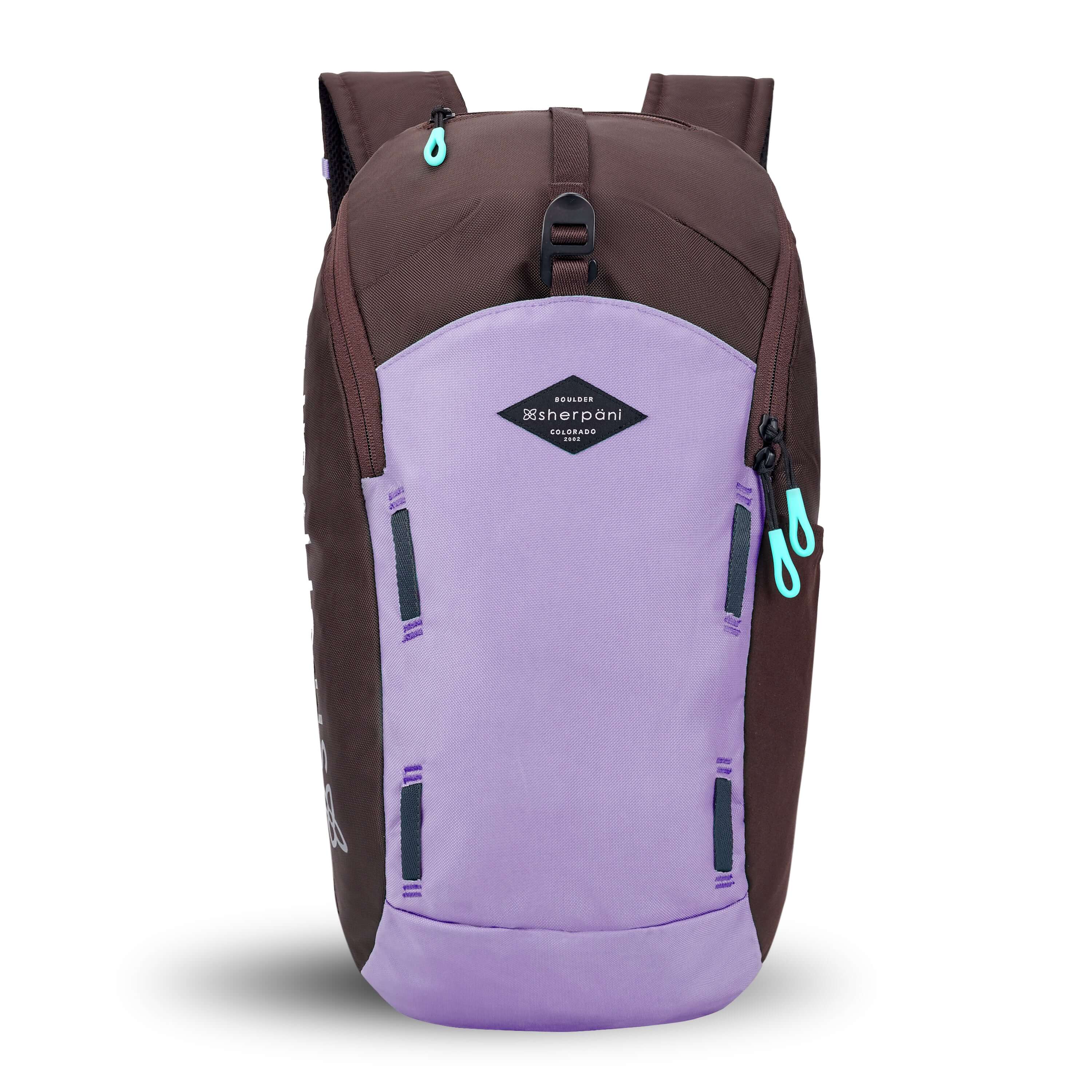 Flat front view of Sherpani backpack, the Switch in Lavender. The bag is two-toned in lavender and brown. Easy-pull zippers are accented in aqua. At the top is a metal buckle that connect to an external pouch on the front panel. It has adjustable and padded backpack straps. There is a daisy chain feature on the front panel. 