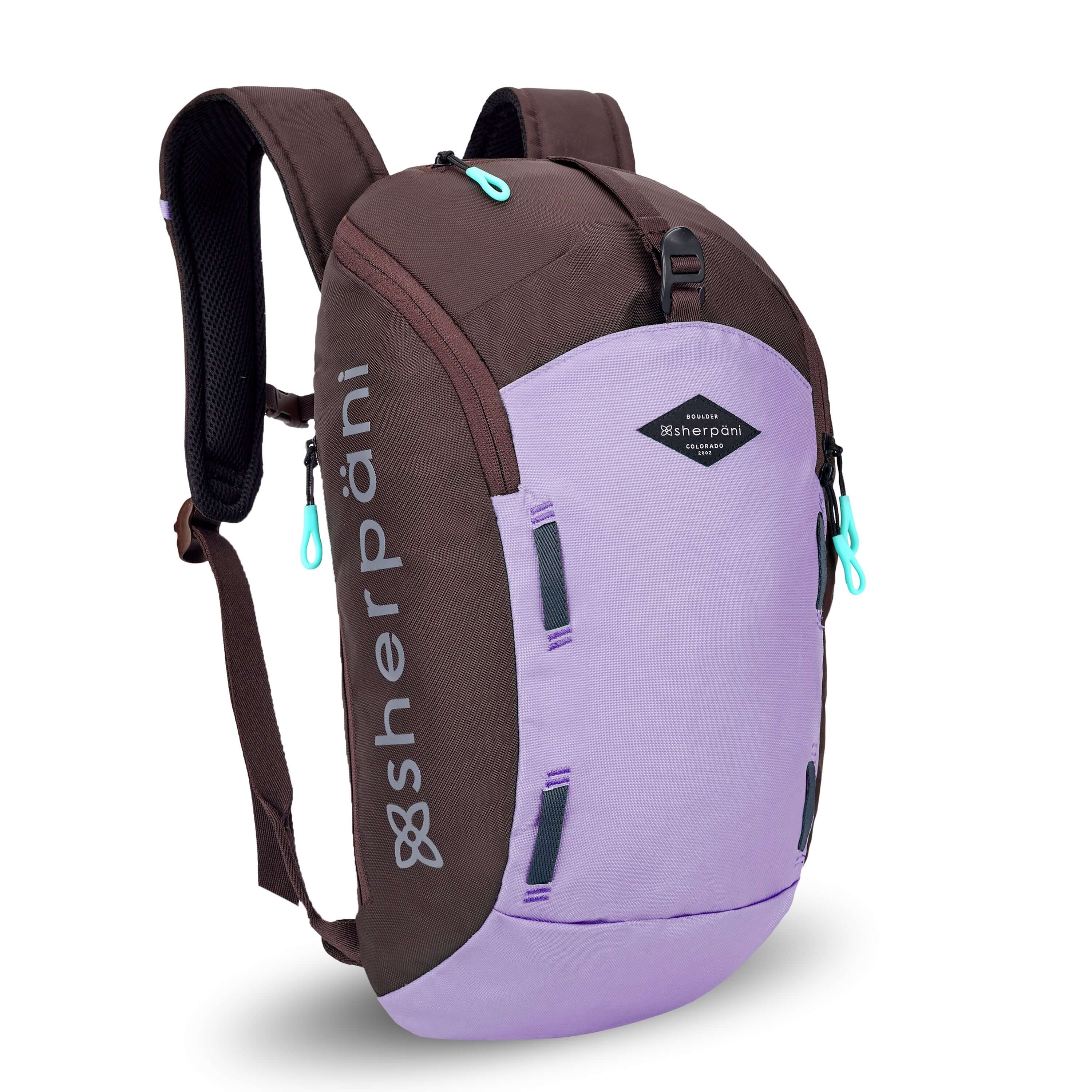 Angled front view of Sherpani backpack, the Switch in Lavender. The bag is two-toned in lavender and brown. Easy-pull zippers are accented in aqua. At the top is a metal buckle that connect to an external pouch on the front panel. It has adjustable and padded backpack straps. There is a daisy chain feature on the front panel.