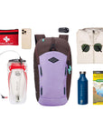 Top view of example items to fill the bag. Sherpani backpack, the Switch in Lavender, lies in the center. It is surrounded by an assortment of items: first aid kit, phone, hydration reservoir, car key, rain jacket, sunglasses, water bottle and hiking guide.