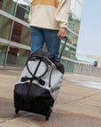 Close up view of a woman walking outside the airport. She is holding the luggage handle of the Trip in Sterling and pulling the large capacity rolling duffle bag along behind her.