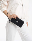 A model holding Sherpani travel wallet with RFID protection, the Tulum in Raven. The wristlet strap is around her wrist.