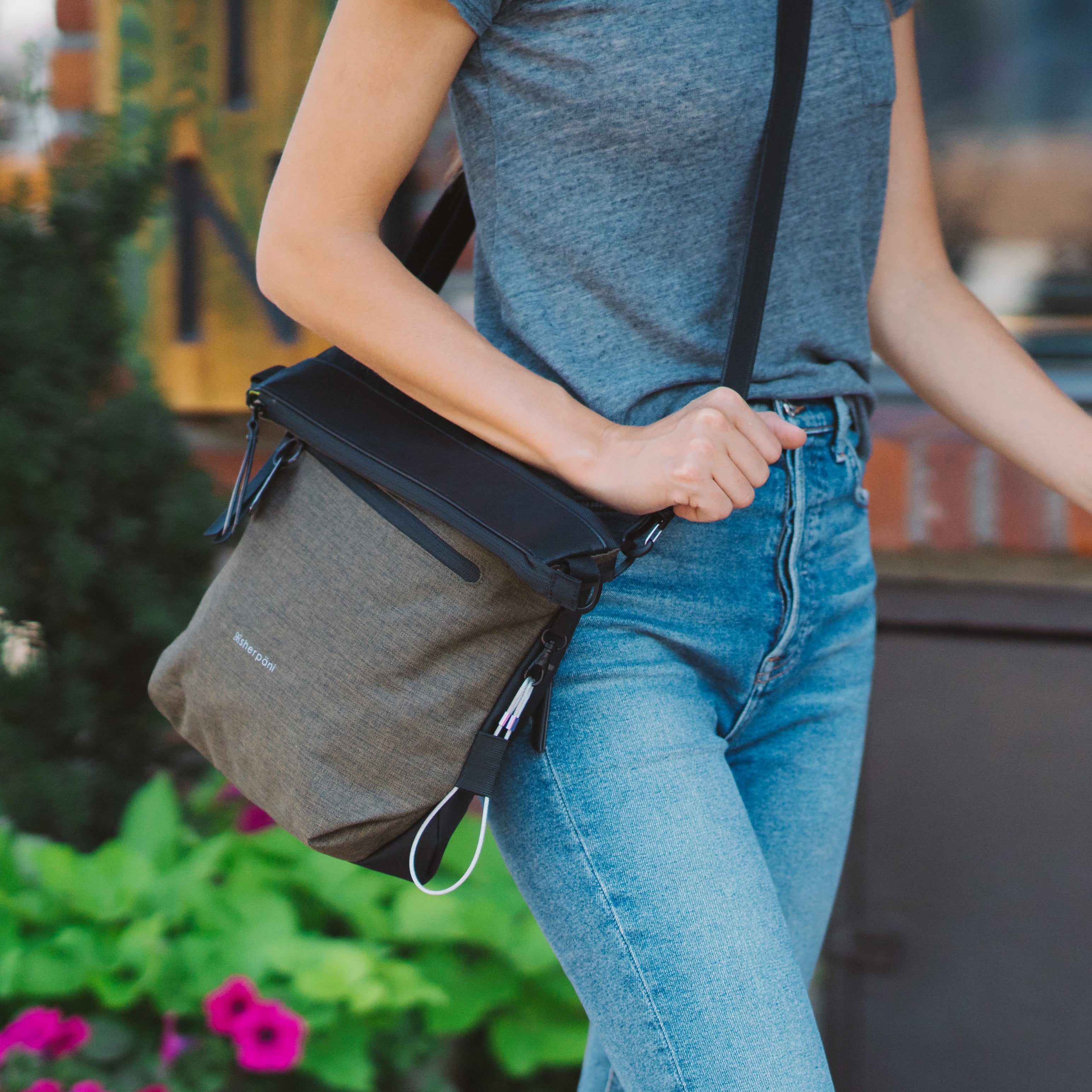 Close up view of a woman walking outdoors with Sherpani reversible bag, the Vale in Loden, as an Anti-Theft crossbody purse. 