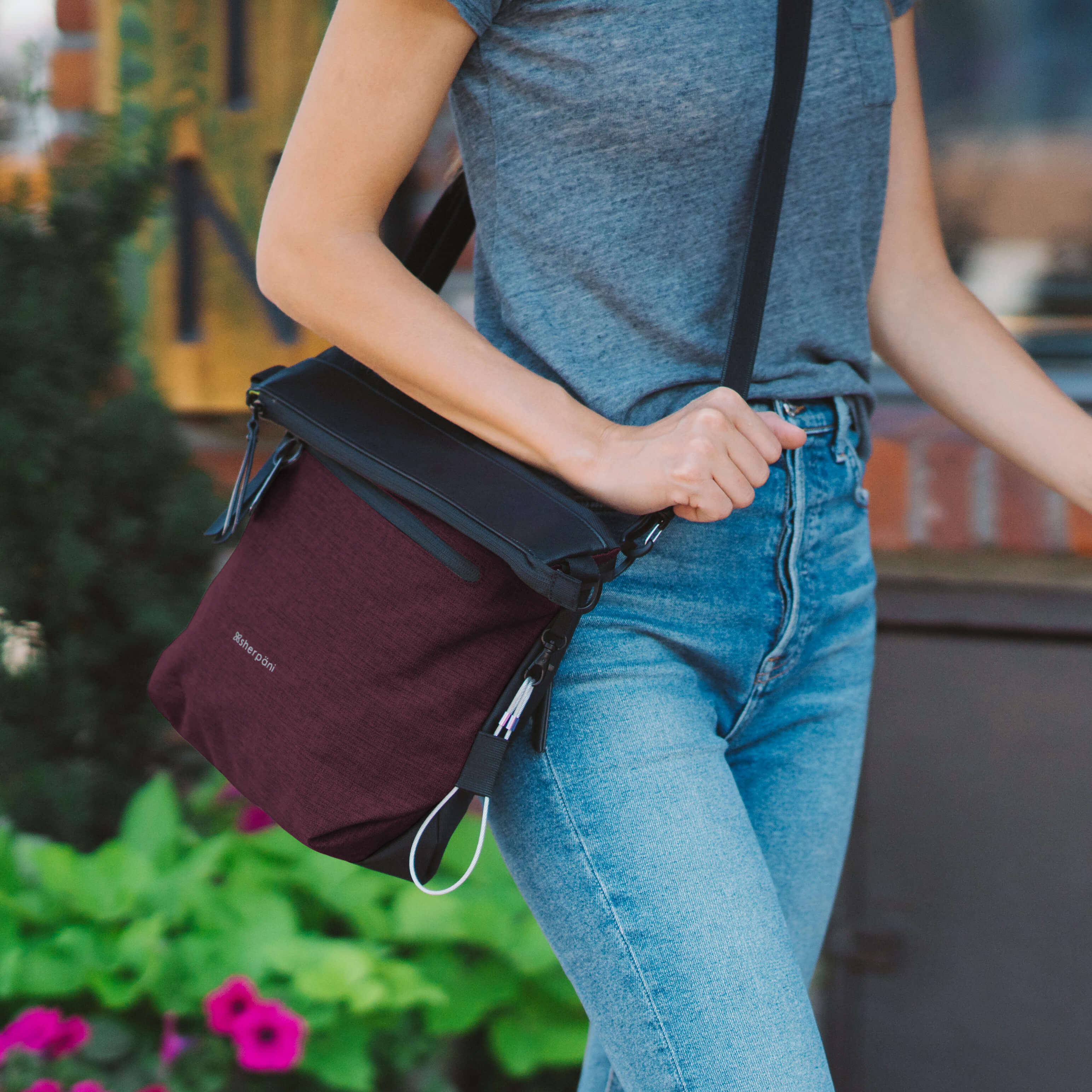 Close up view of a woman walking outdoors with Sherpani reversible bag, the Vale in Merlot, as an Anti-Theft crossbody purse. 
