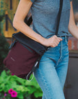 Close up view of a woman walking outdoors with Sherpani reversible bag, the Vale in Merlot, as an Anti-Theft crossbody purse.