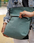 Close up view of a model's hands. She is unzipping the external compartment of Sherpani's Anti-Theft bag the Vale AT in Teal.
