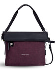 Flat front view of Sherpani's Anti-Theft bag, the Vale AT in Merlot with vegan leather accents in black. The top is folded over creating a two-toned reversible overlap. A chair loop lock is clipped onto one side, secured in place by an elastic tab. A ReturnMe tag is attached to the front zipper compartment. It has an adjustable/detachable crossbody strap, and a second detachable strap fixed at a shorter length.
