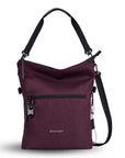 Flat front view of Sherpani's Anti-Theft bag, the Vale AT in Merlot with vegan leather accents in black. The bag is standing tall with a detachable tote strap clipped to the top. There is an adjustable/detachable crossbody strap and a chair loop lock is clipped to the side of the bag. The front features an external compartment with a locking zipper and ReturnMe tag.