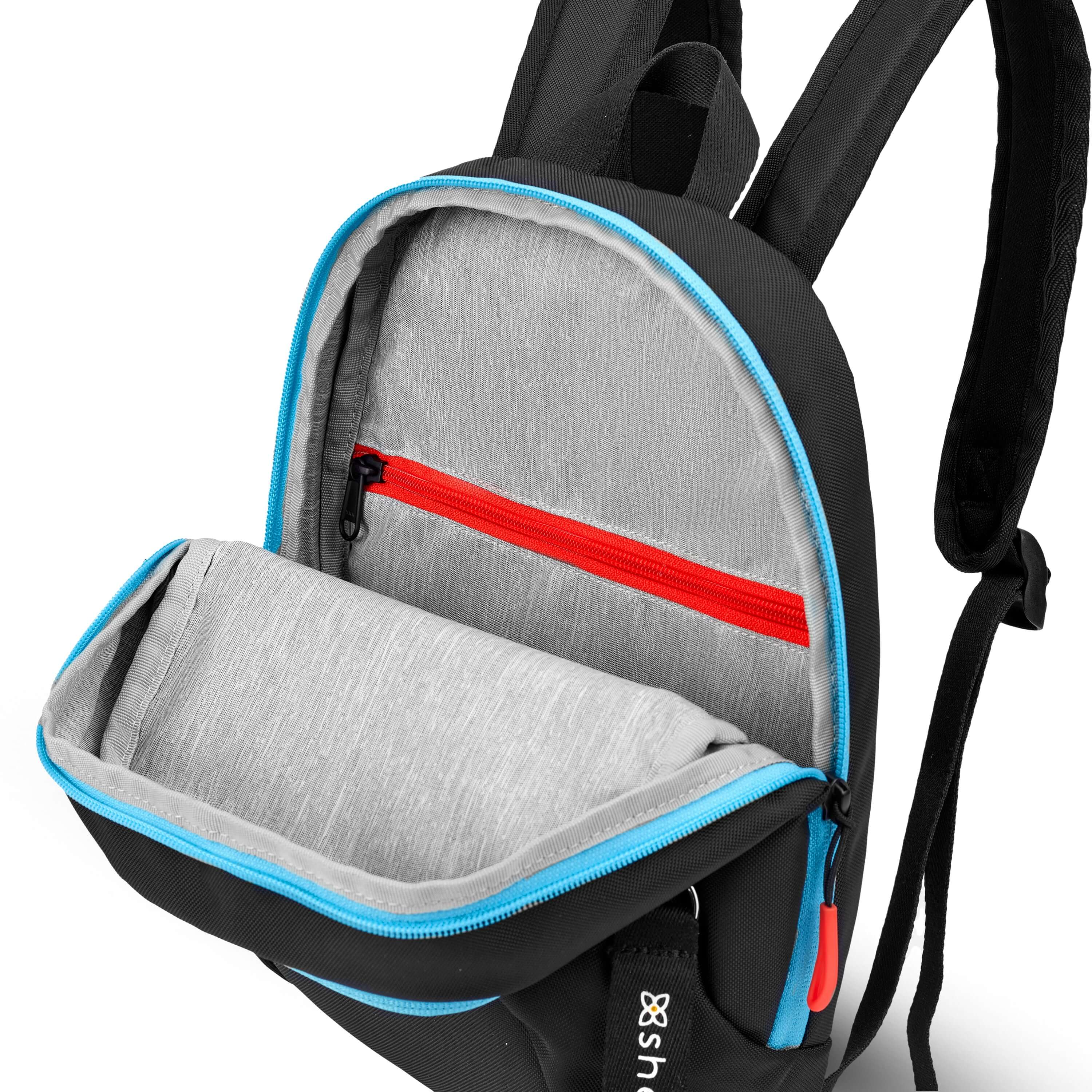 Top view of Sherpani mini backpack, the Vespa in Chromatic. The main zipper compartment is open to reveal a light gray interior and internal zipper pocket.