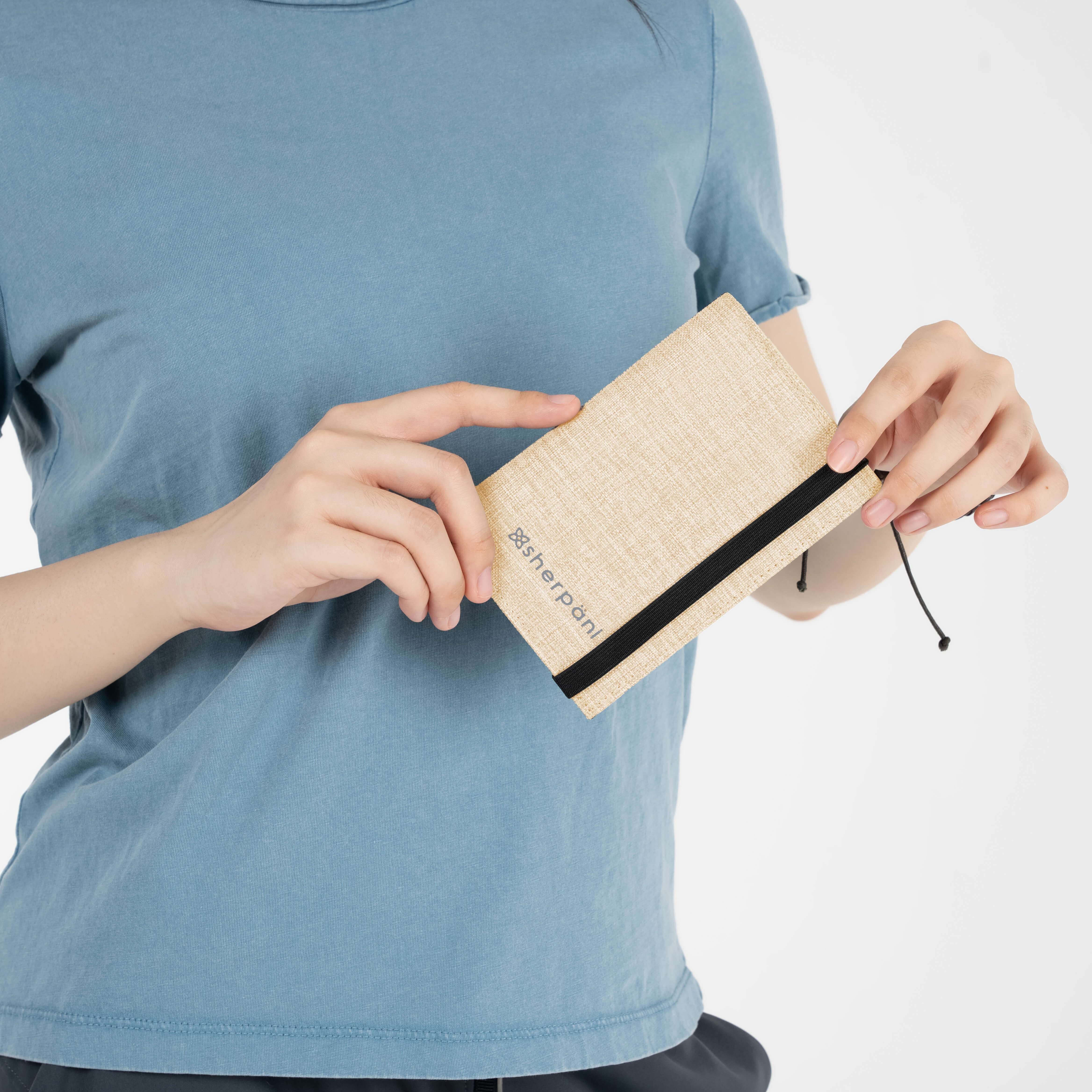 Model holding RFID passport protector by Sherpani, the Vienna in Straw. 