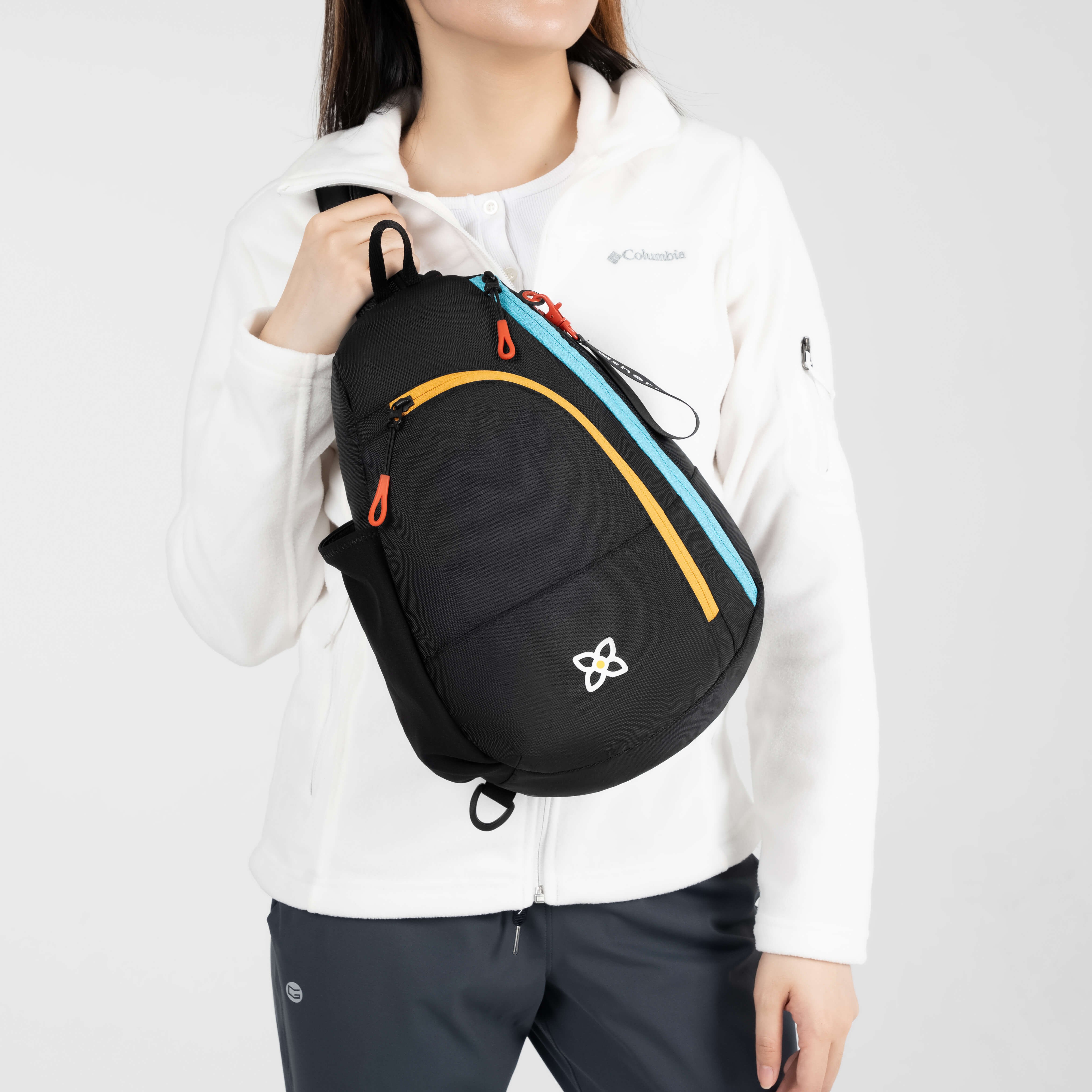 A model holding the medium sized sling backpack, the Wayfarer in Chromatic. 