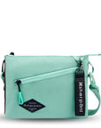 Flat front view of Sherpani crossbody, the Zoom in Seagreen. The bag is two-toned; the front half is light gray and the back half is brown. There is an external zipper pocket on the front with an easy-pull zipper accented in light green. The bag has an adjustable/detachable crossbody strap. There is a branded Sherpani keychain clipped to a fabric loop on the upper right corner.