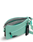 Top view of Sherpani crossbody, the Zoom in Seagreen. The main zipper compartment is open to reveal an internal divider that separates the bag into dual compartments. The inside of the bag is light gray with zipper pockets accented in light green.