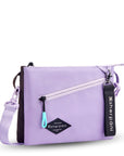 Angled front view of Sherpani crossbody, the Zoom in Lavender. The bag is two-toned; the front half is lavender and the back half is brown. There is an external zipper pocket on the front with an easy-pull zipper accented in aqua. The bag has an adjustable/detachable crossbody strap. There is a branded Sherpani keychain clipped to a fabric loop on the upper right corner.
