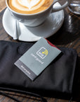 On top of a table with a coffee, the card guard in Juniper sits on top of Sherpani RFID wallet, the Tulum.