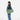 Woman wearing a Sherpani Jaunt Olivine Green Garment Duffle by the crossbody strap against white backdrop #color_olivine-green